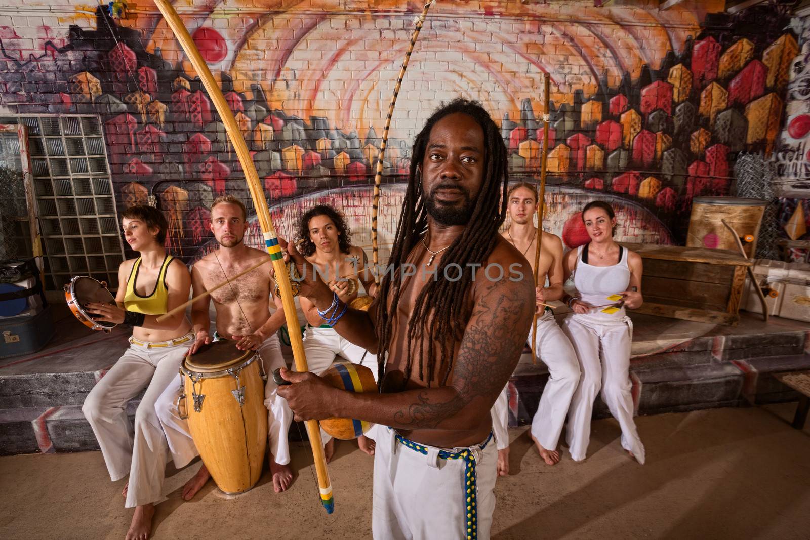Capoeira teacher with dreadlocks and students playing music 