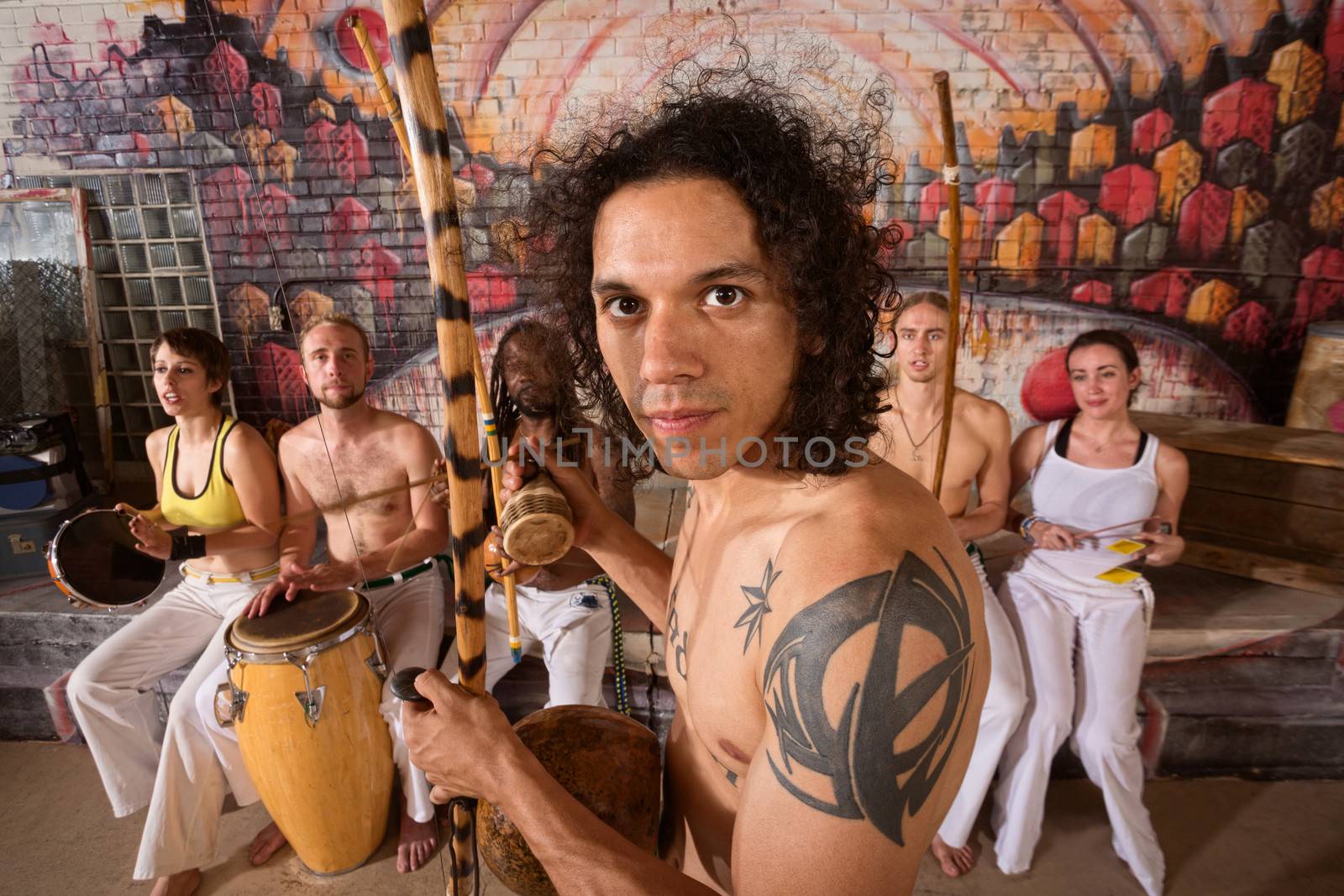 Handsome Latino capoeira expert with tattoo and musical instrument