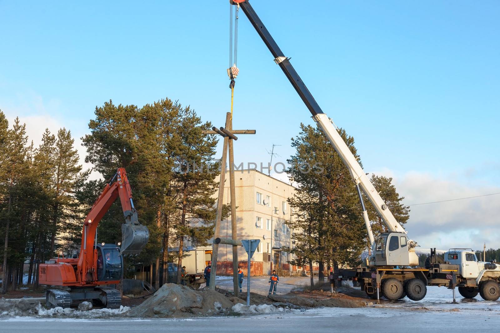 Installing a power pole on the outskirts of the settlements with the use of a truck crane and excavator