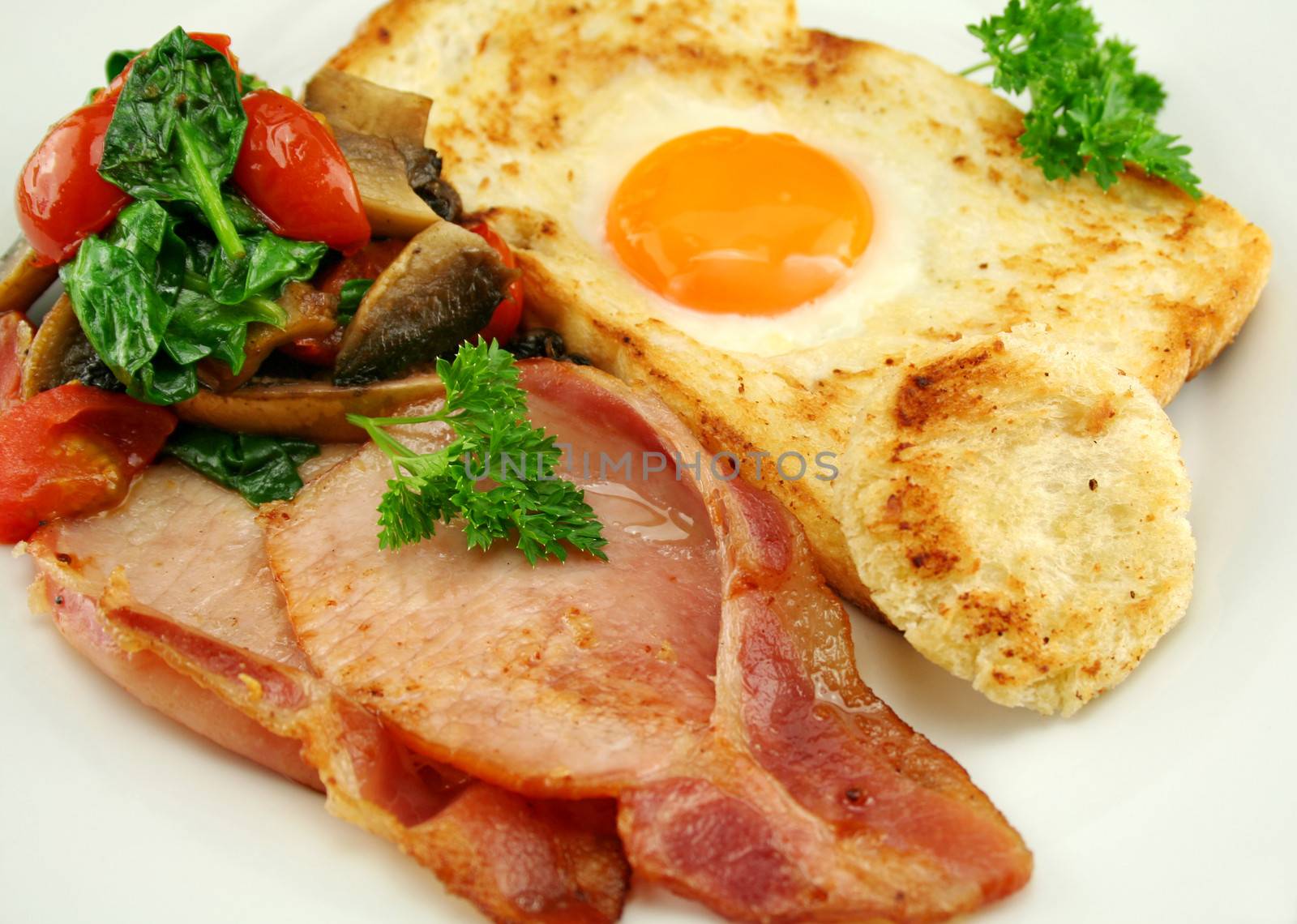 Egg embedded in toast with bacon, mushrooms, spinach and tomatoes.