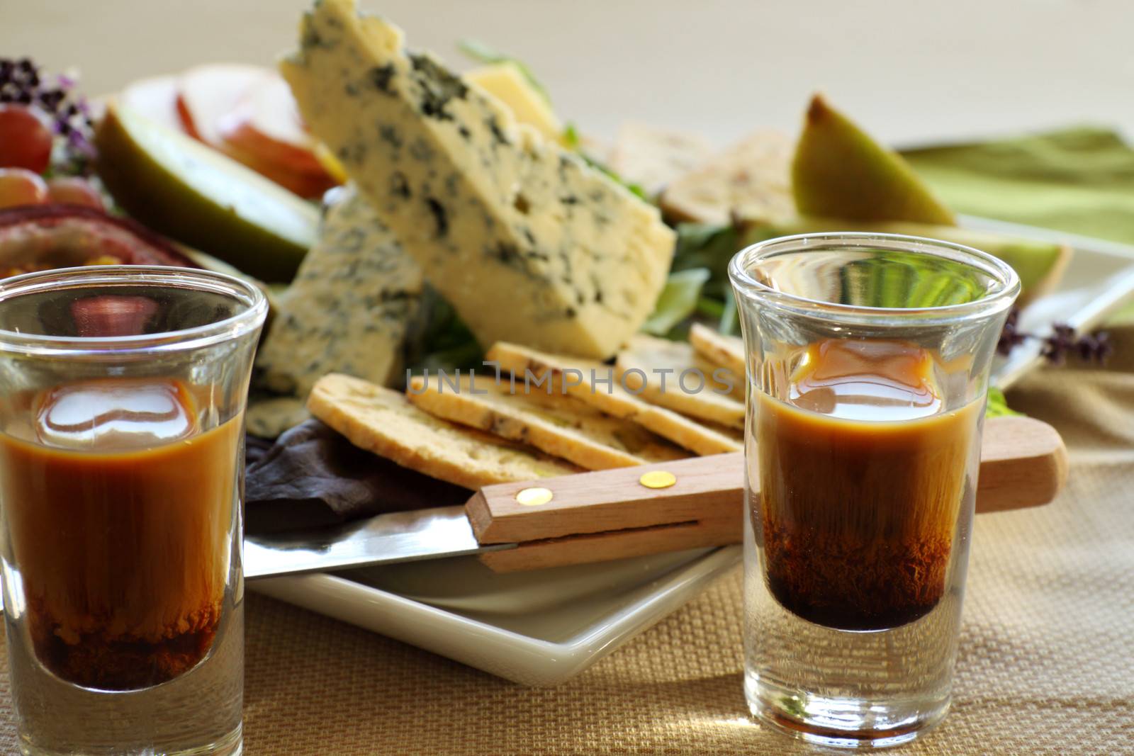 Delicious fruit and cheese platter featuring different cheeses and fresh fruits with a coffee liquer.
