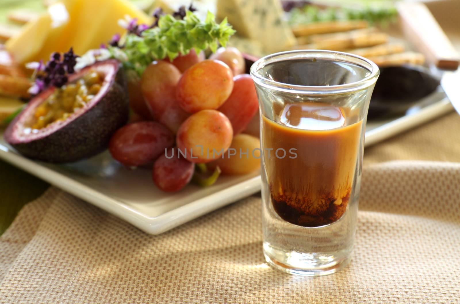 Delicious fruit and cheese platter featuring different cheeses and fresh fruits with a coffee liquer.