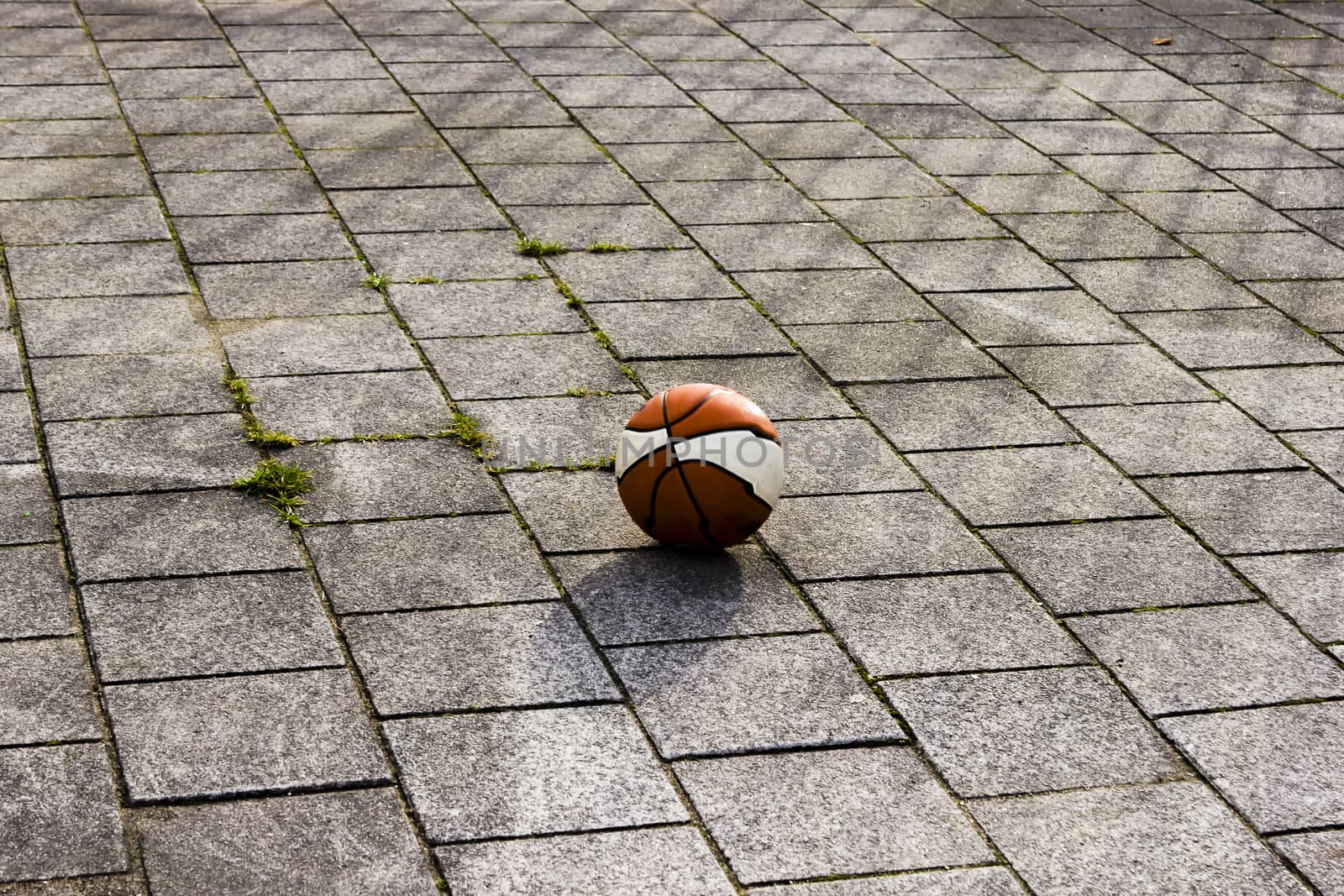Basketball ball on the playground in sunlight by Tetyana
