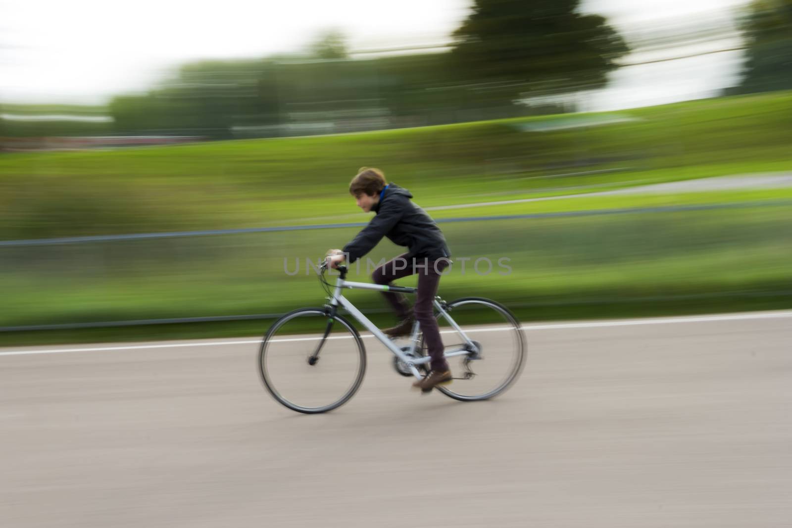 Boy riding a bike in a park by Tetyana