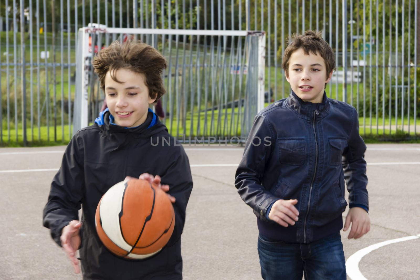 Two boys playing basketball  in the playground by Tetyana