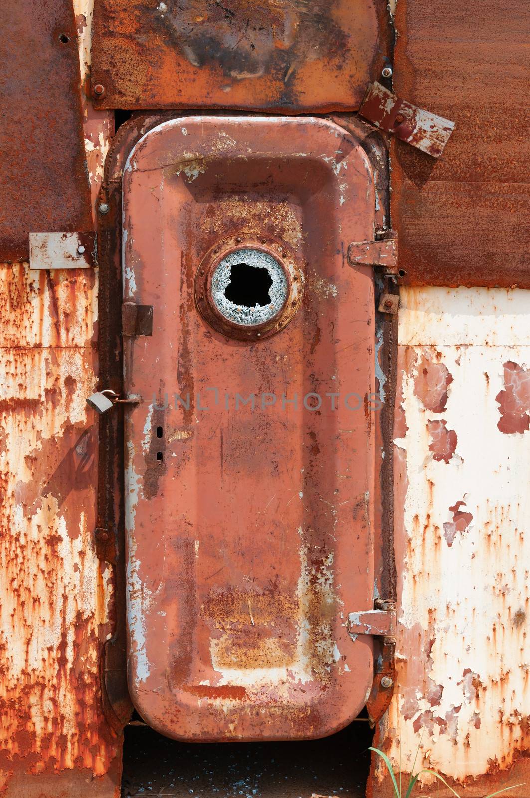 Rusty closed door on metal wall of wrecked abandoned ship 
