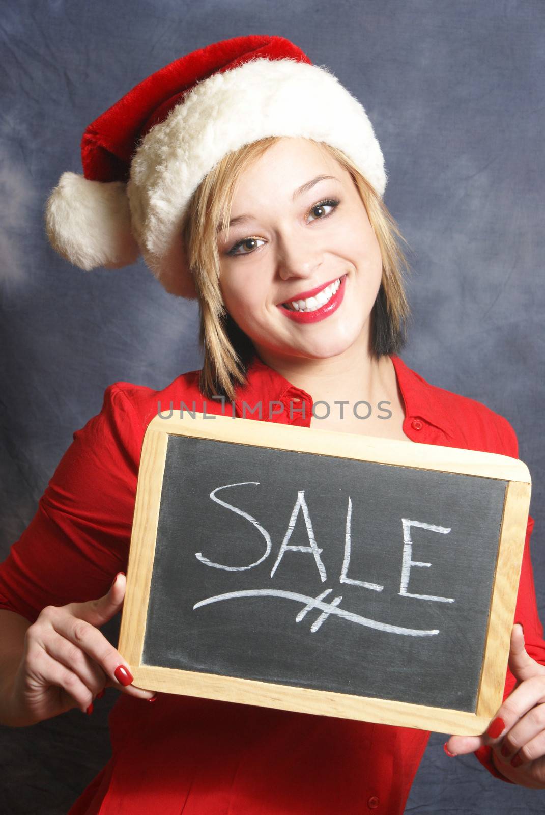 An attractive young woman displays a sale sign for the Christmas season.