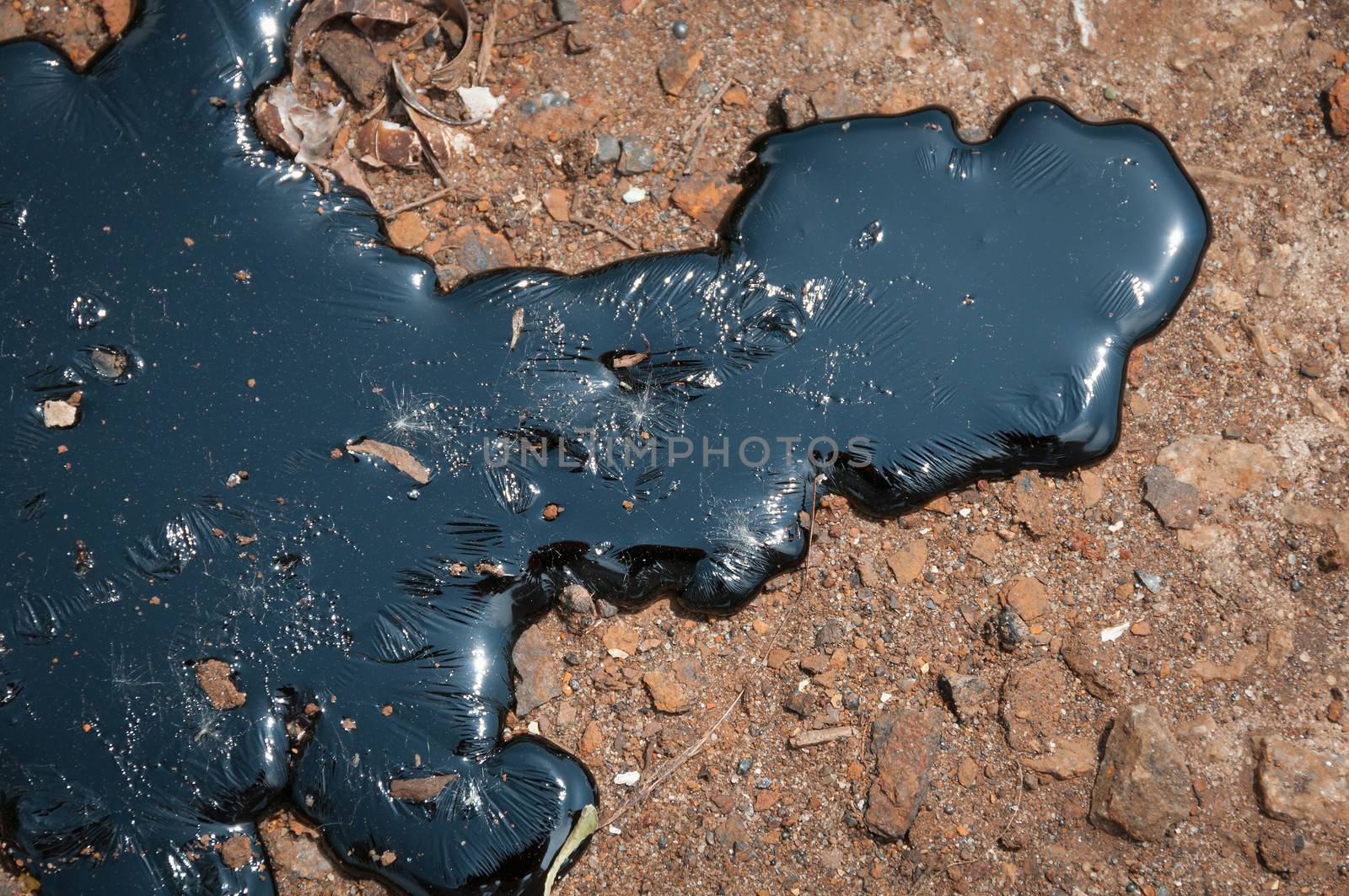 Black oily liquid pitch against the brown earth fuse under heat sun