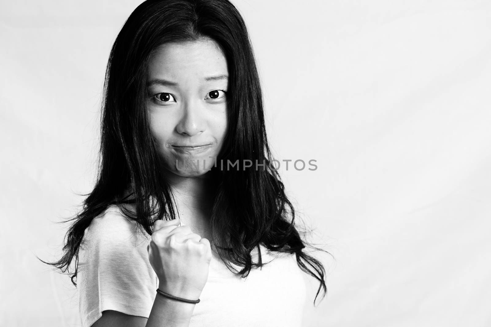 Portrait of attractive young woman clenching her fist for encouragement, black and white style