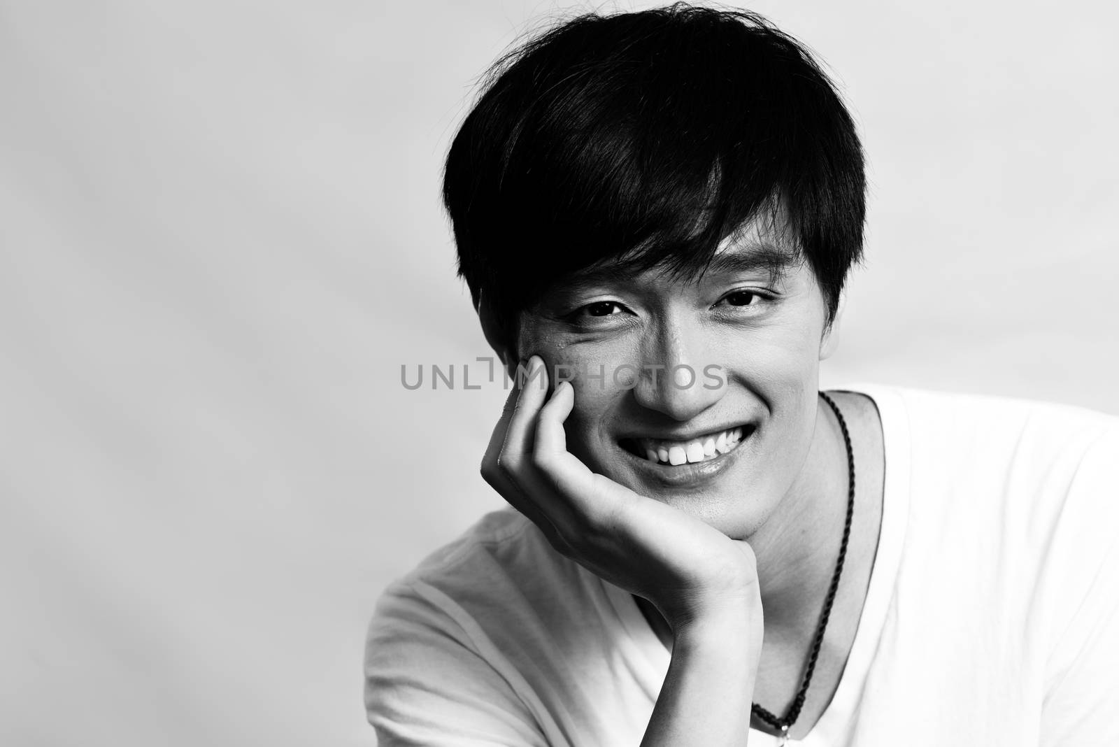 Portrait of young man supporting chin and smiling, black and white style