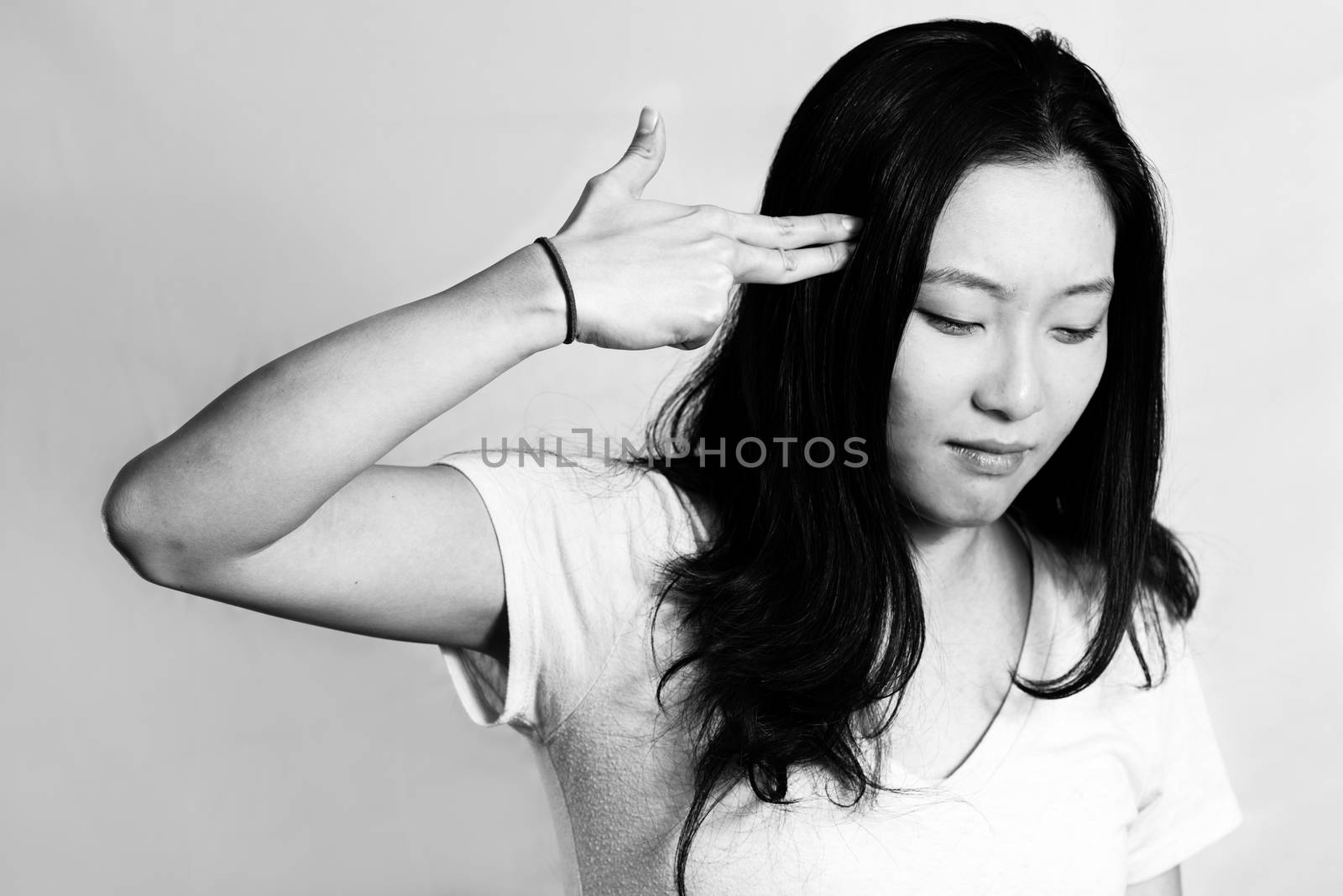 Portrait of depressed young woman hand signals suicide, black and white style