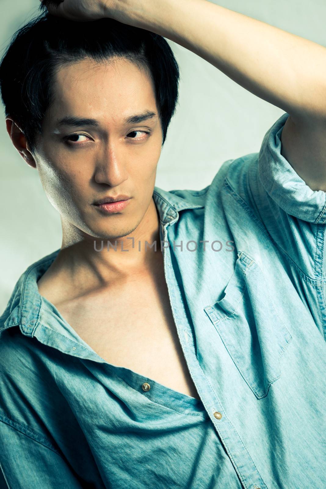 Studio fashion pose by a handsome young male model, with fashion tone and background