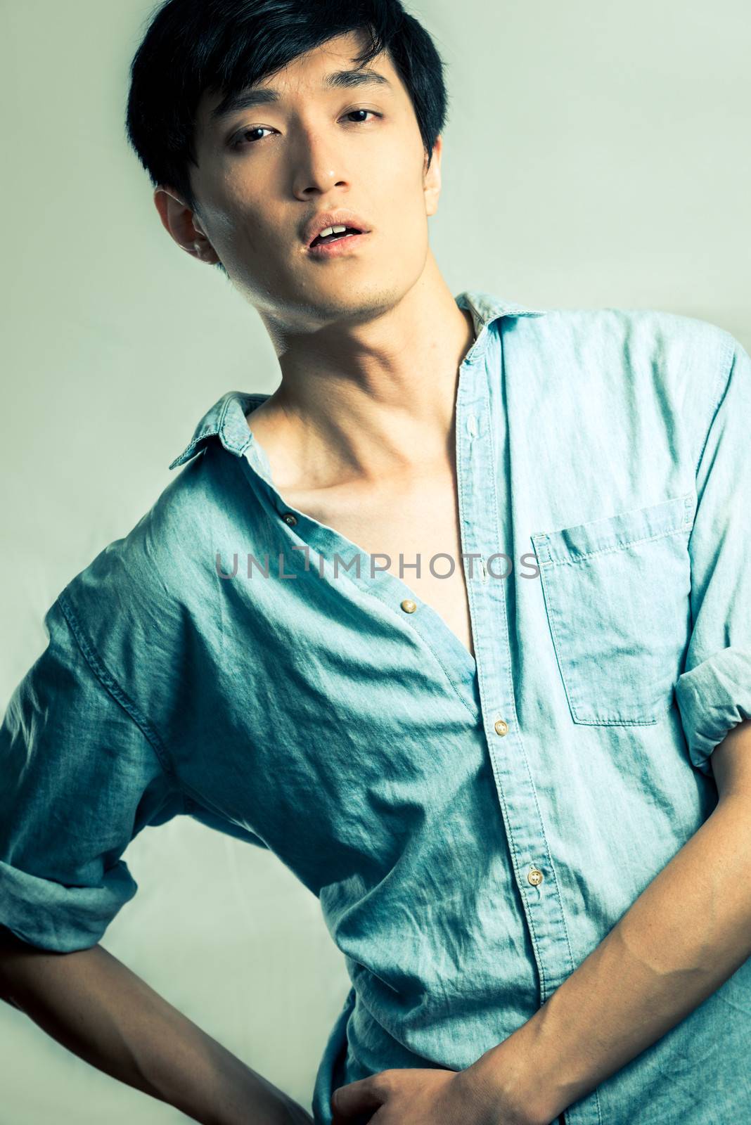 Studio fashion pose by a handsome young male model, with fashion tone and background