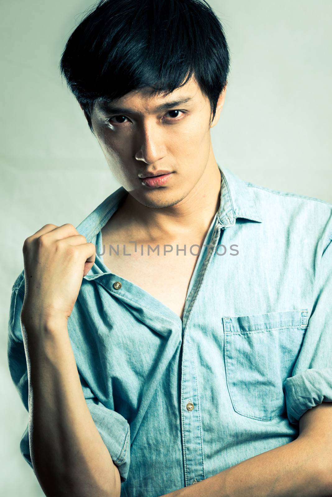 Studio fashion pose by a handsome young male model, with fashion tone and background