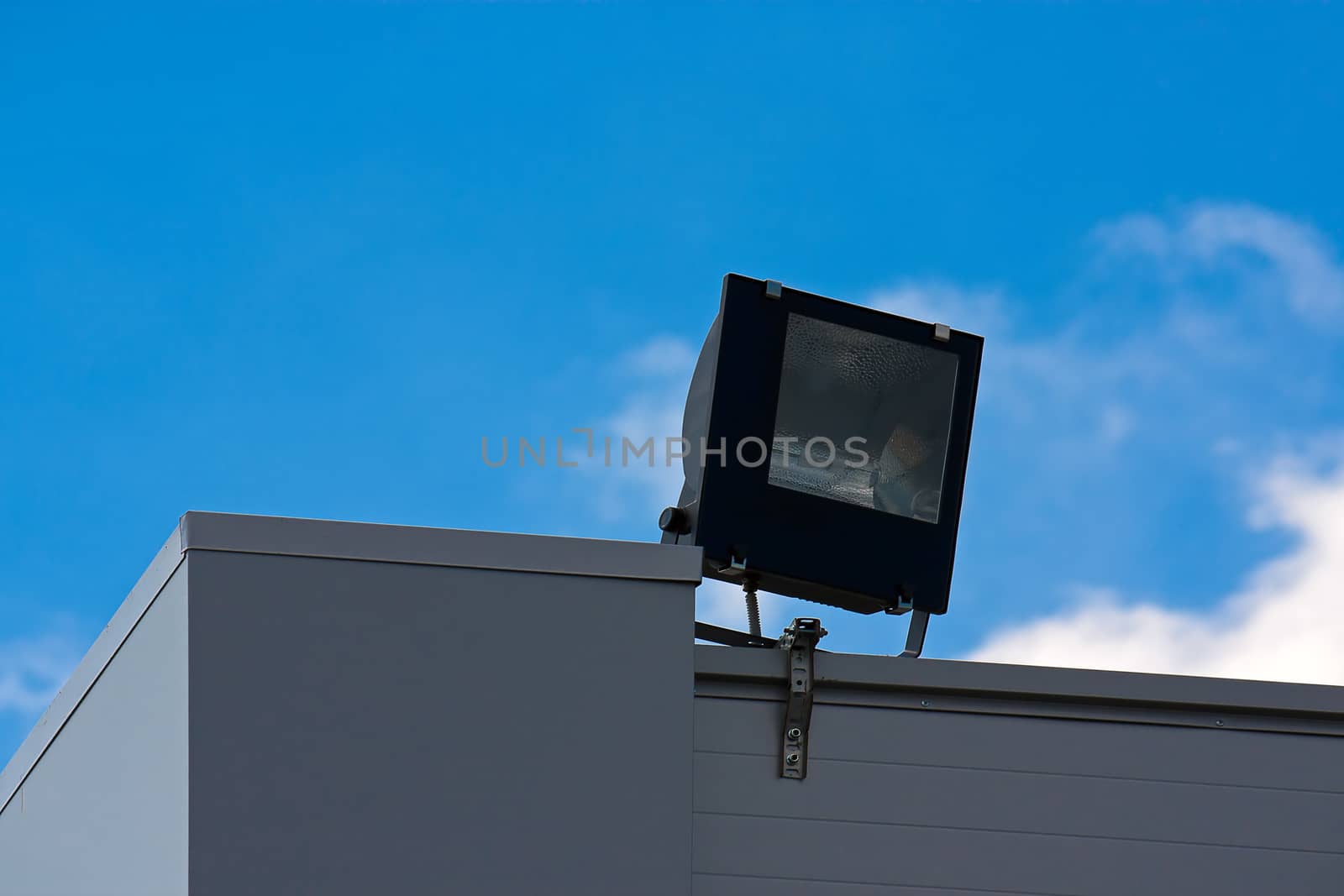 Halogen projector close up to  roof of  building against  blue sky.