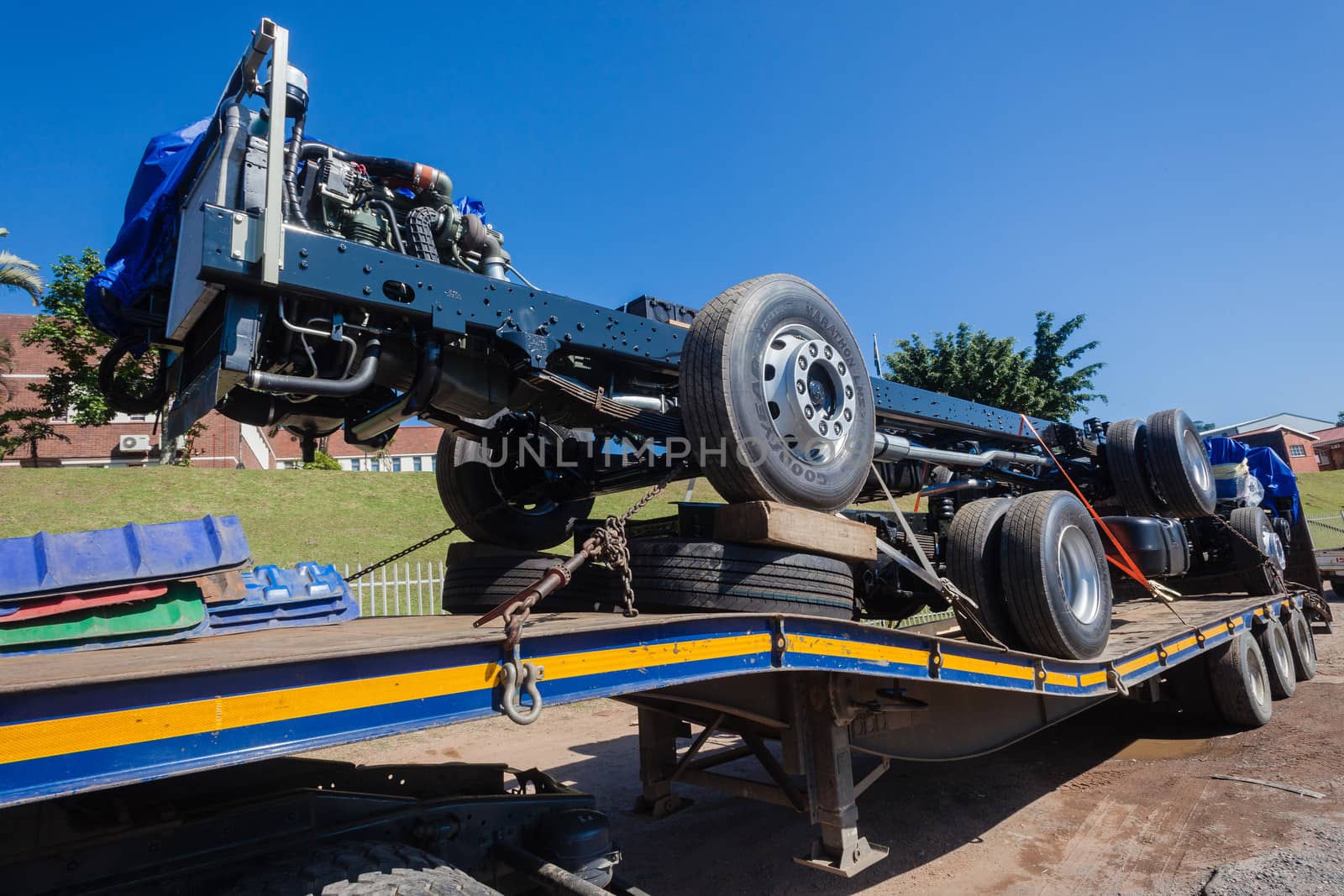 New built truck chassis frame wheels and engines on transport trailer.