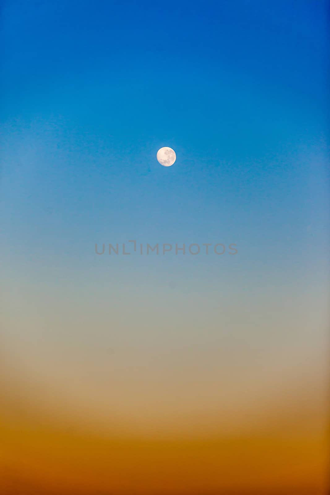 Full moon with colors in the early morning blue sky