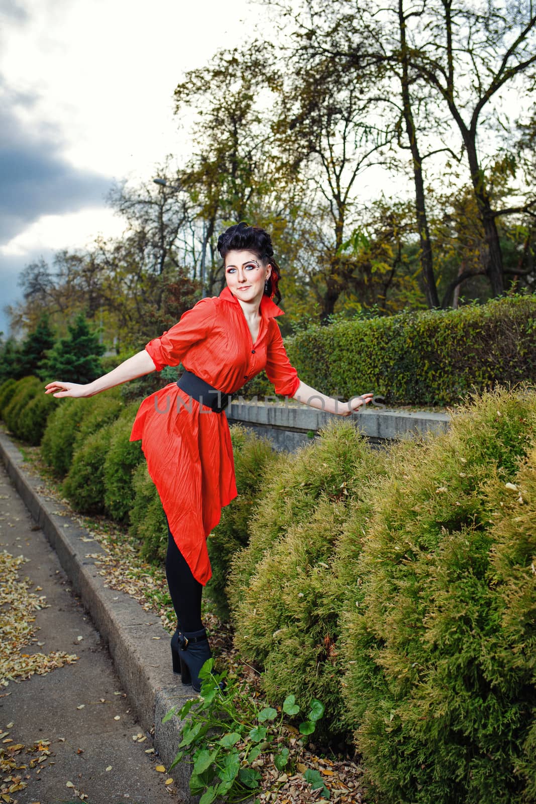 Attractive young girl in a red shirt walks in the city park