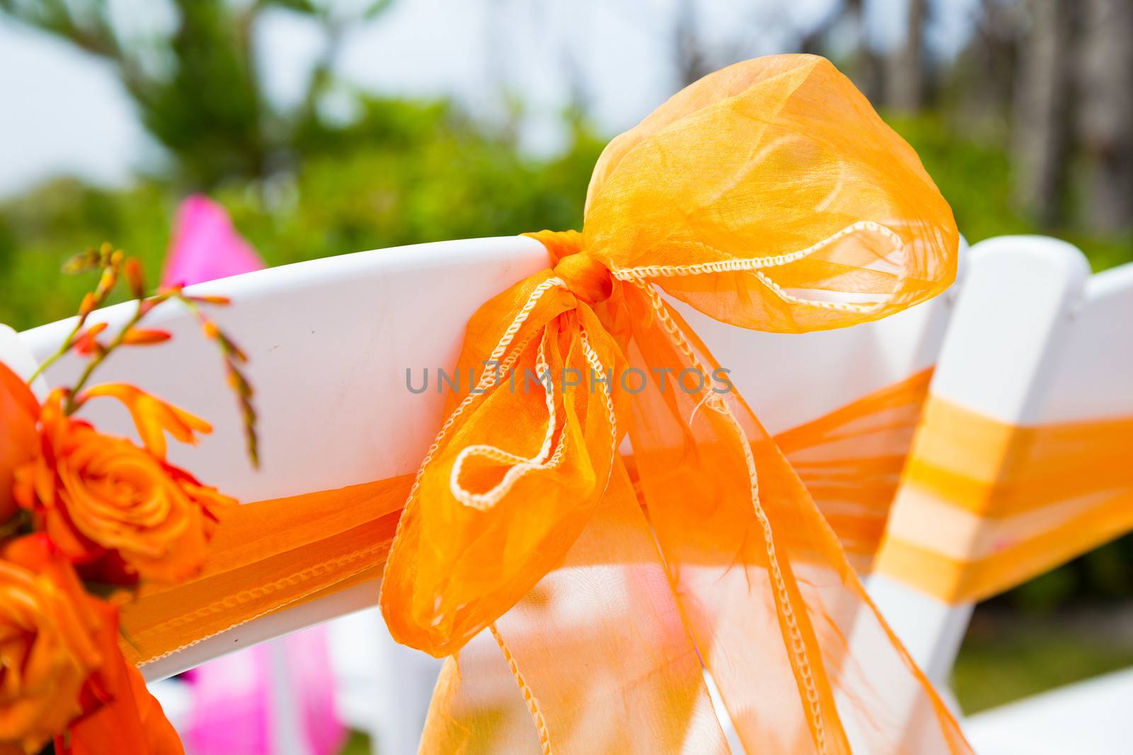 Bows and fabric are tied together to create decorations for this outdoor coastal summer wedding with vibrant colors.