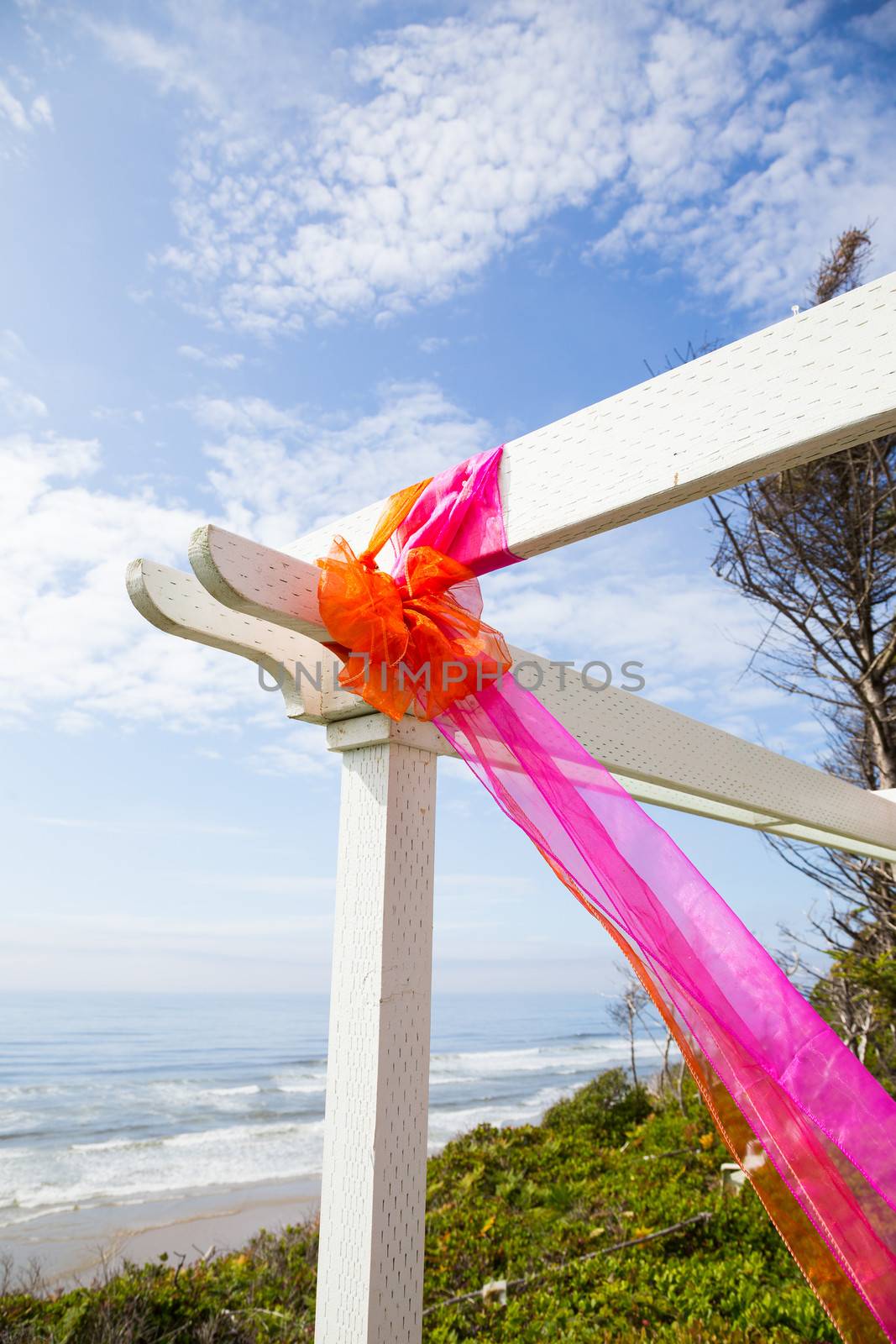 Bows and fabric are tied together to create decorations for this outdoor coastal summer wedding with vibrant colors.