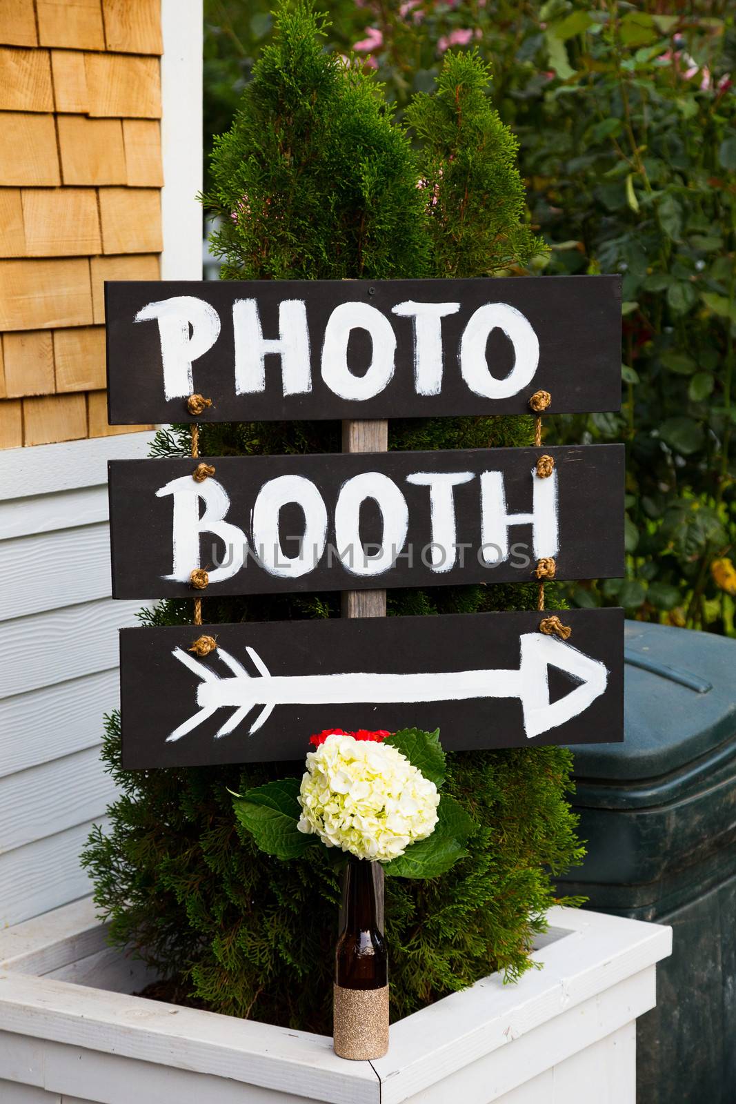 A handmade sign reads photo booth with an arrow pointing the wedding guests to the photobooth location.