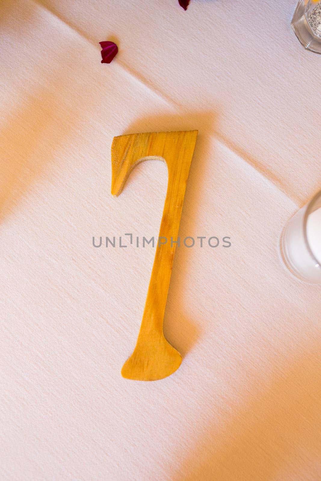 A wooden number 7 or seven is carved out of the wood at a wedding.