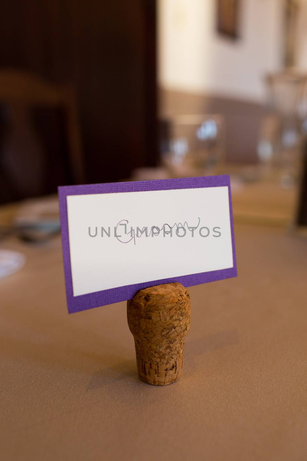 A small sign says groom standing up using a champagne cork as a stand.