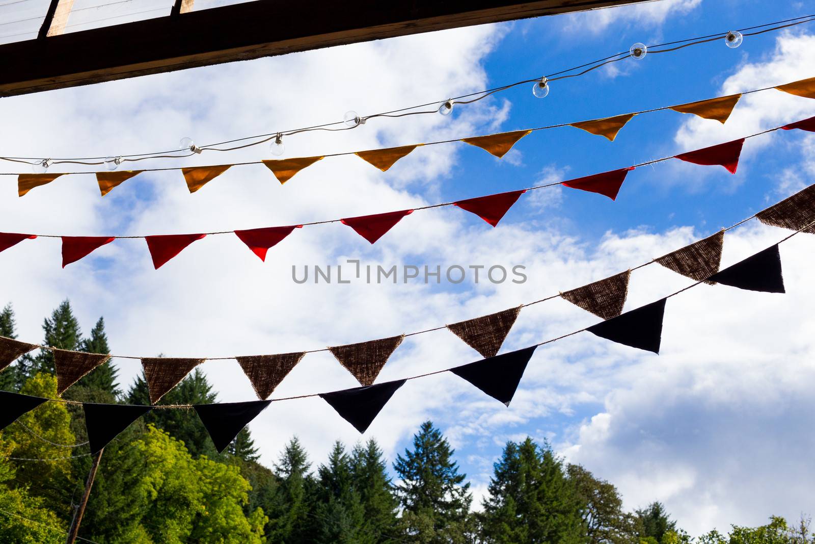 Wedding decor consists of multi colored flags in red, burlap, yellow, and blue for this outdoor country wedding ceremony and reception.