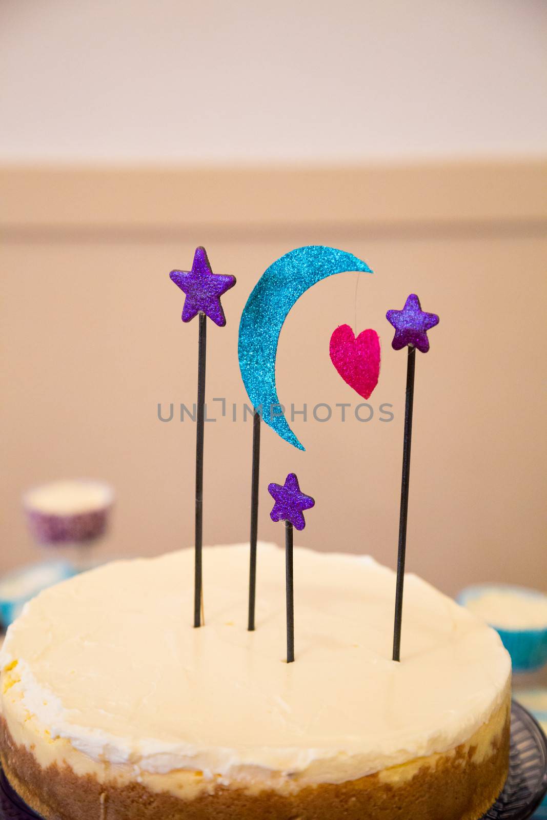 This handmade cake topper has a moon, heart, and stars on it above a wedding cheesecake.