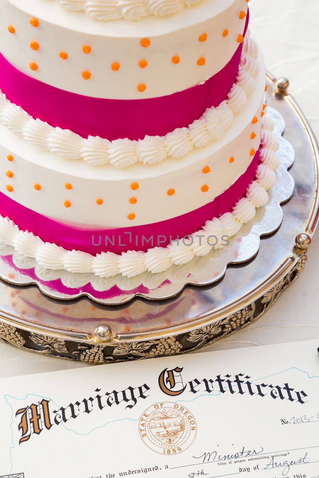 A wedding cake sits next to the bride and groom marriage certificate at this ceremony and reception.