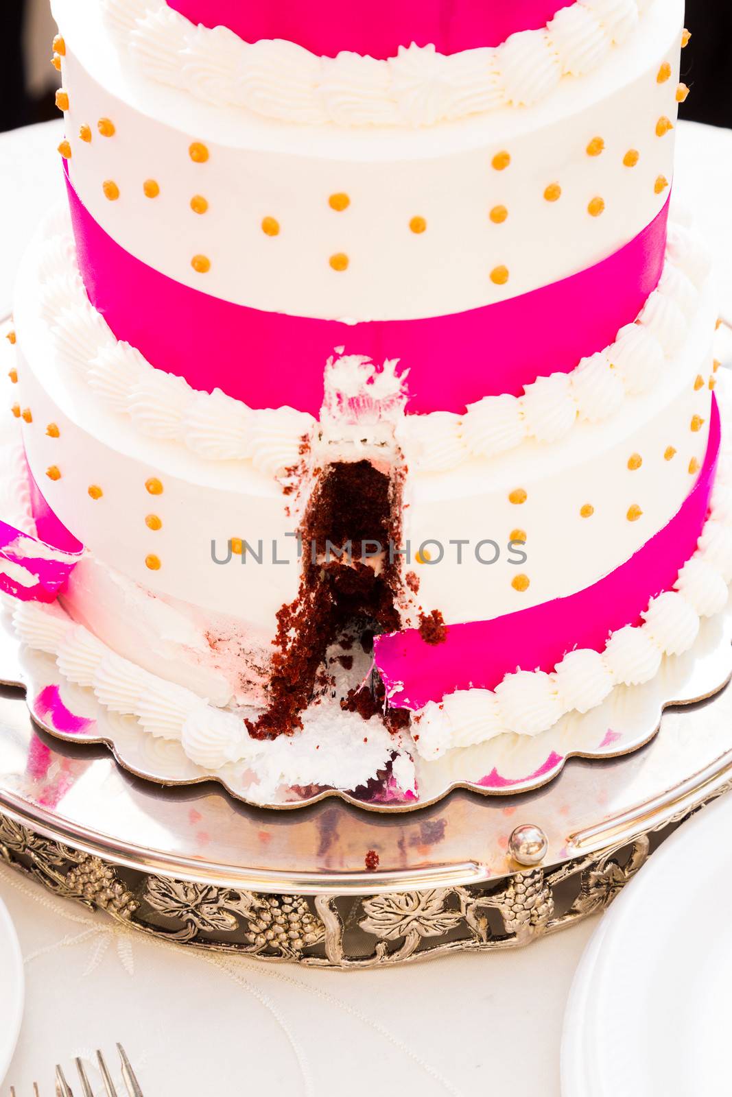 A wedding cake has a missing slice after the bride and groom cut the cake at their reception.