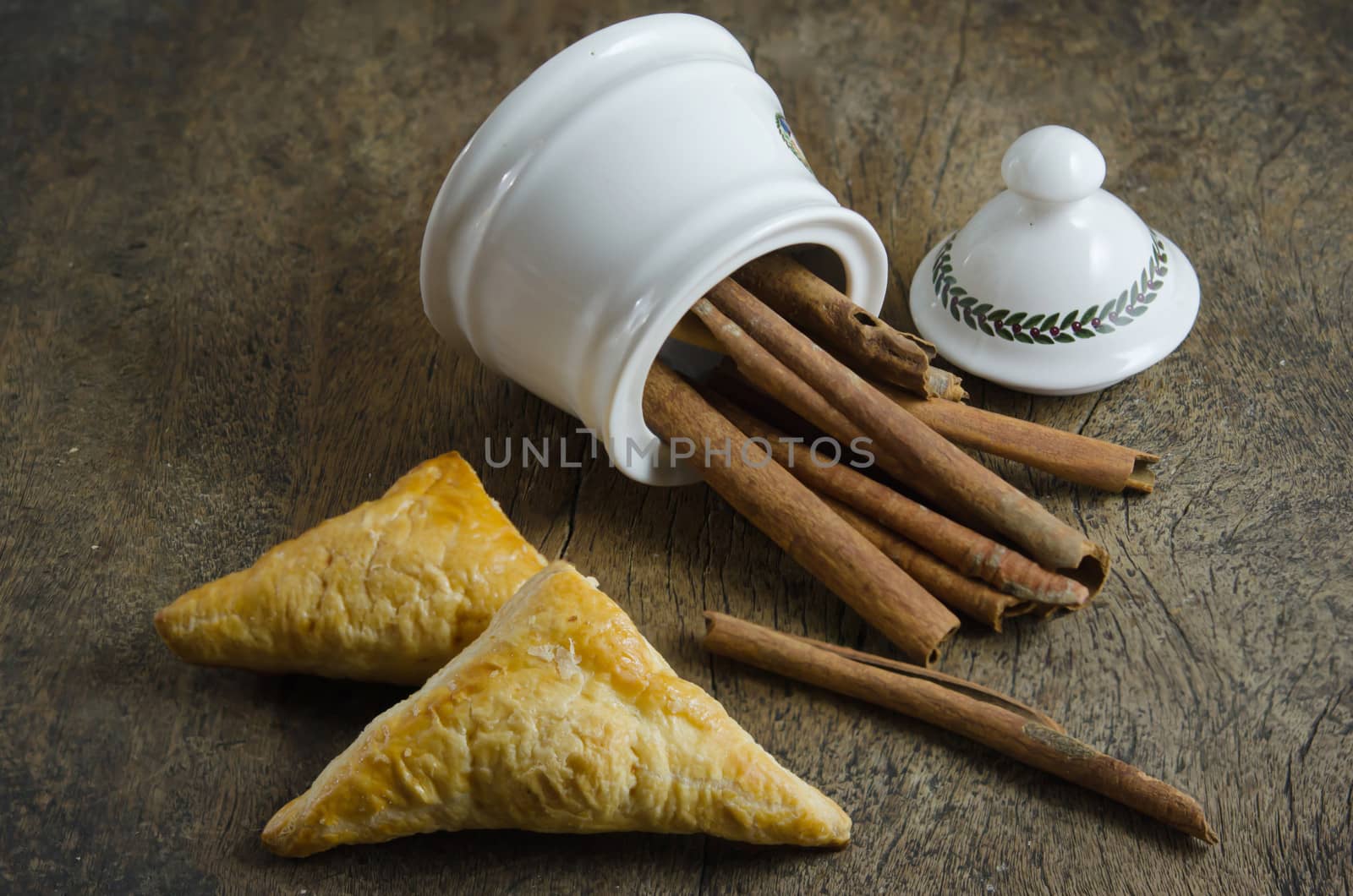 White  bowl with cinnamon sticks and puffed pastry on wooden background