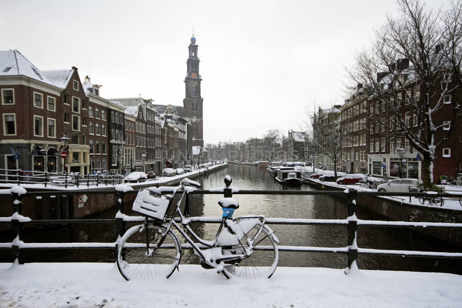 Amsterdam covered with snow with the Westerkerk in winter in the Netherlands