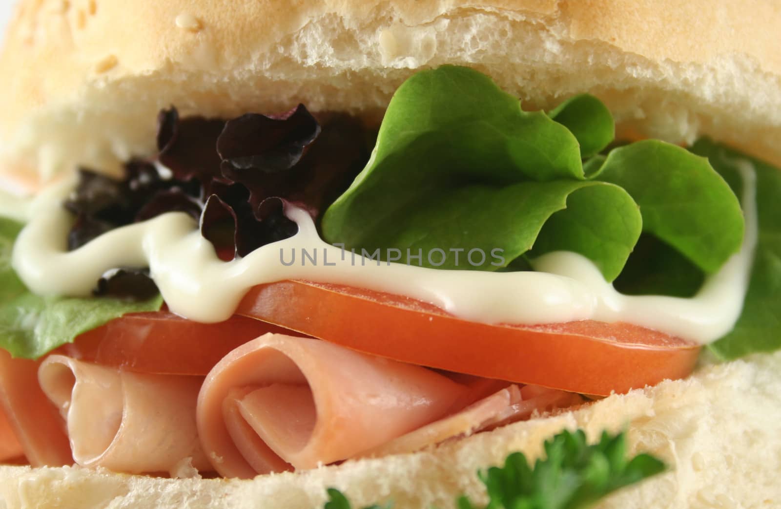 Freshly prepared ham and salad roll with mayo.