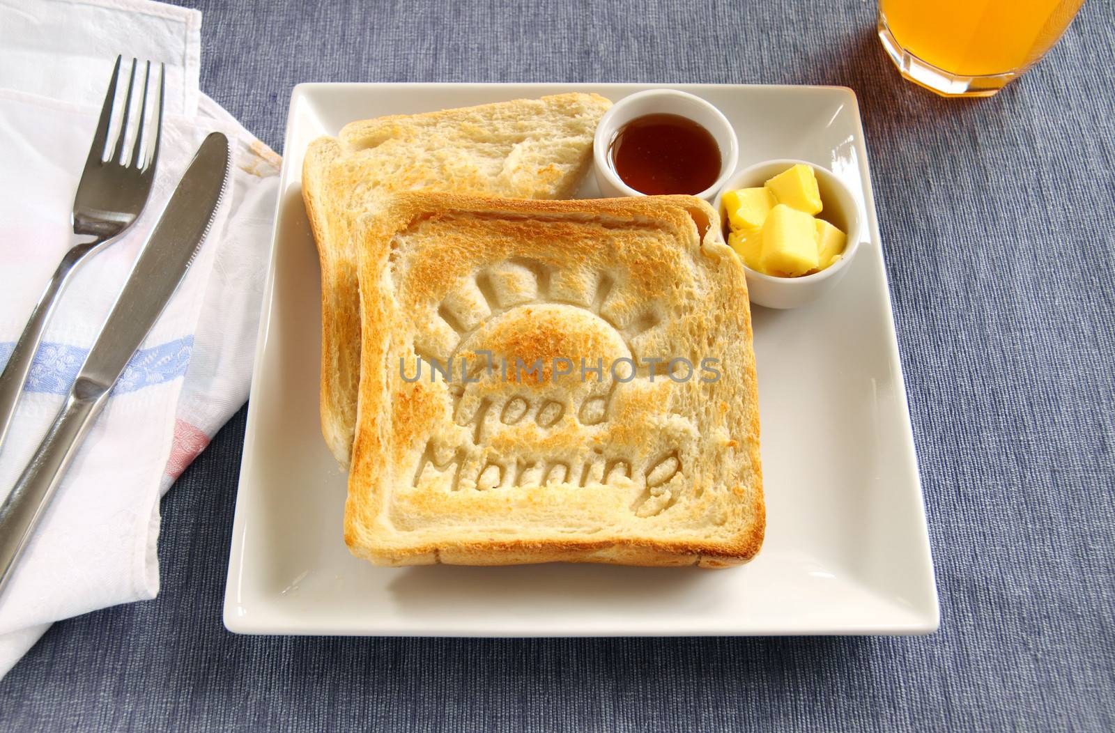 Slice of toast with Good Morning carved into it with butter and honey.