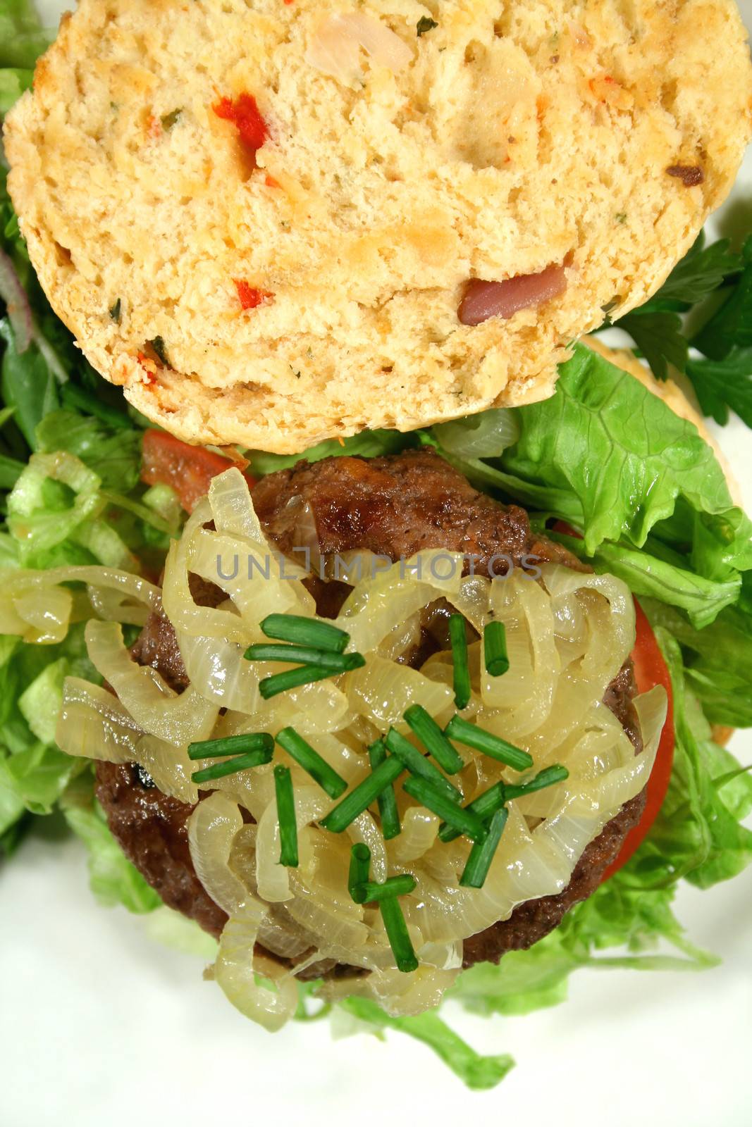 Gourmet beef burger on a fresh homemade herb roll with caramelized onion.