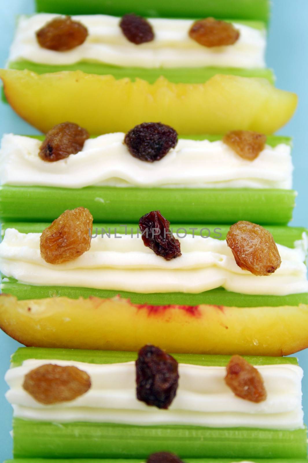 Healthy afternoon snack of celery sticks with cream cheese and sultanas.
