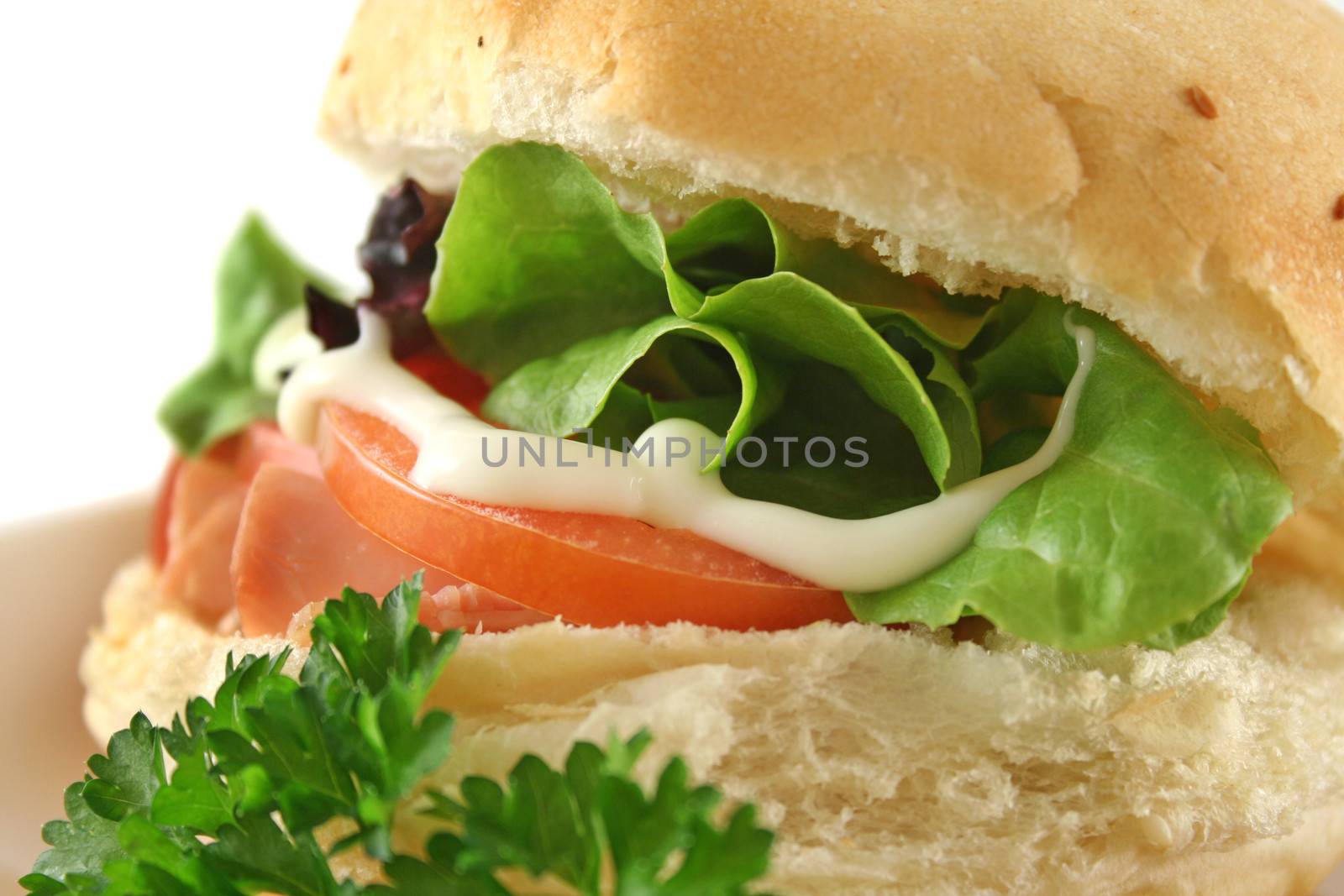 Freshly prepared ham and salad roll with mayo.