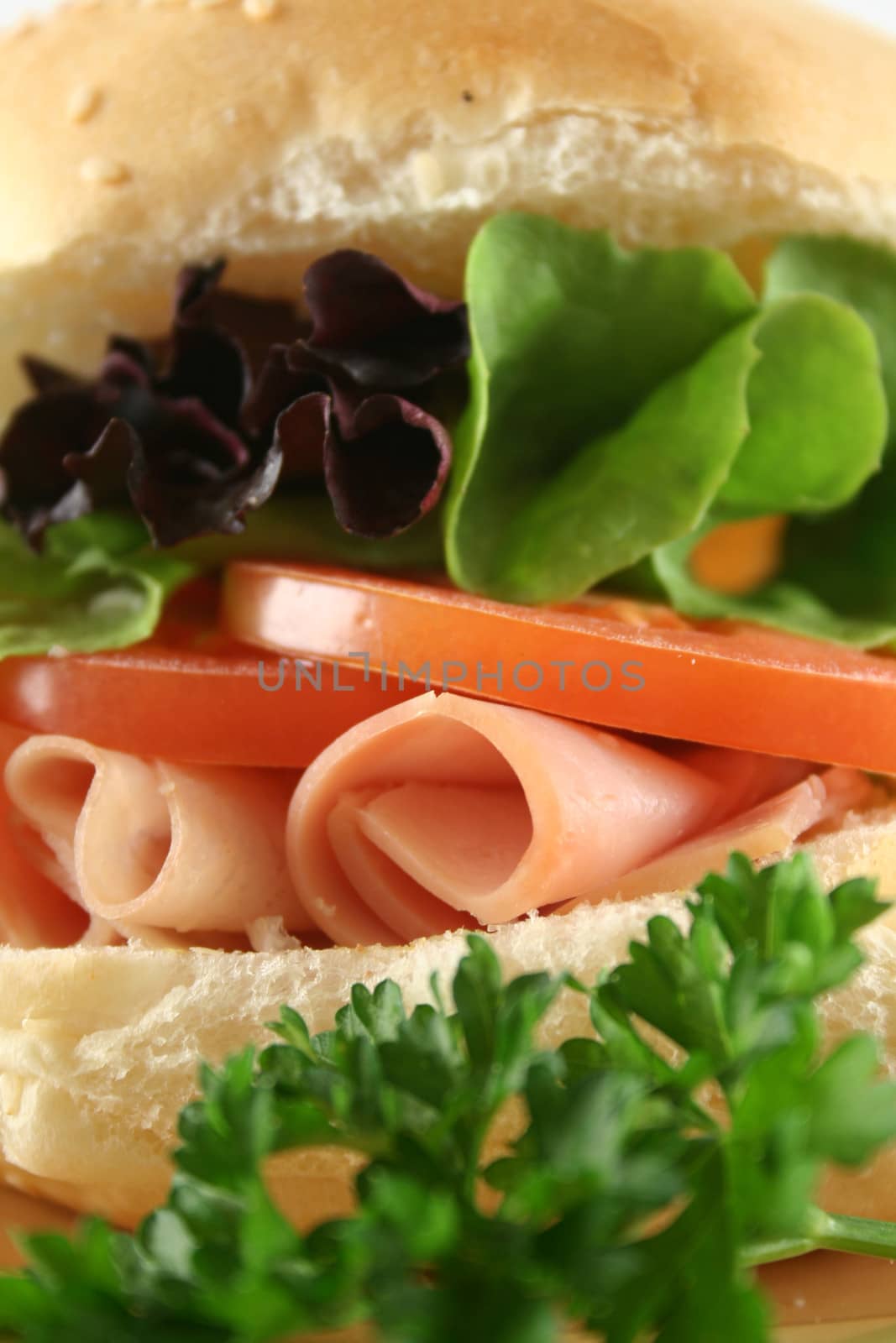 Freshly prepared ham and salad roll with sesame seeds.