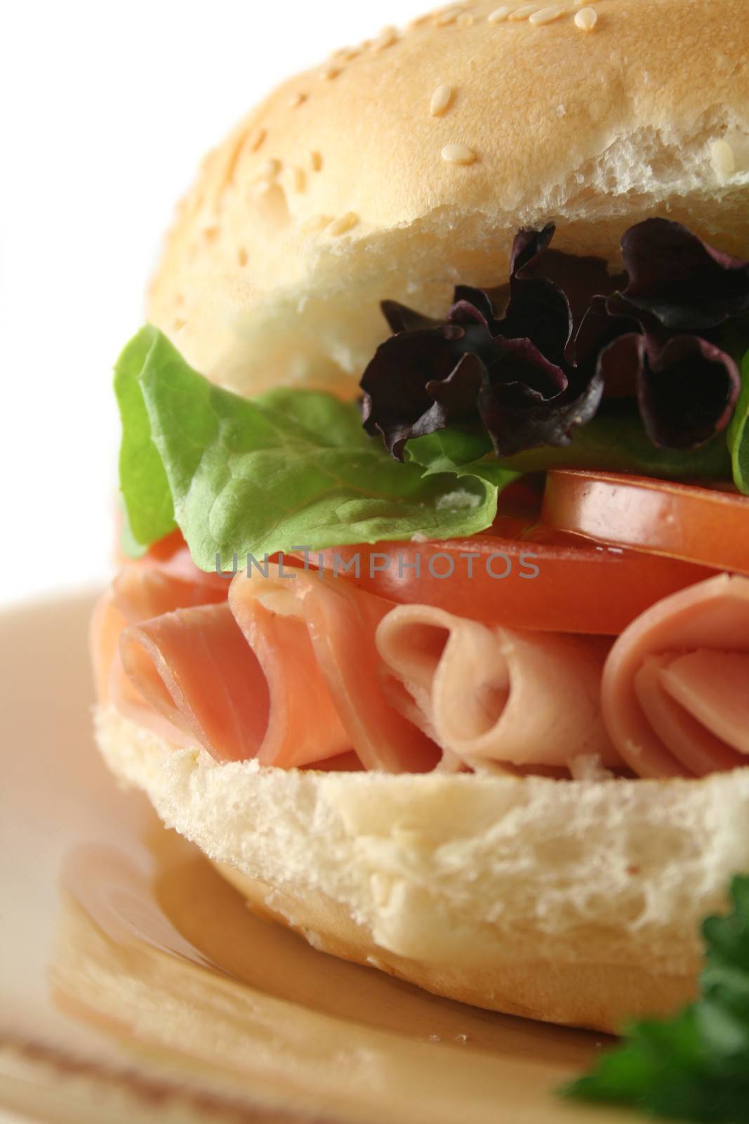 Freshly prepared ham and salad roll with sesame seeds.