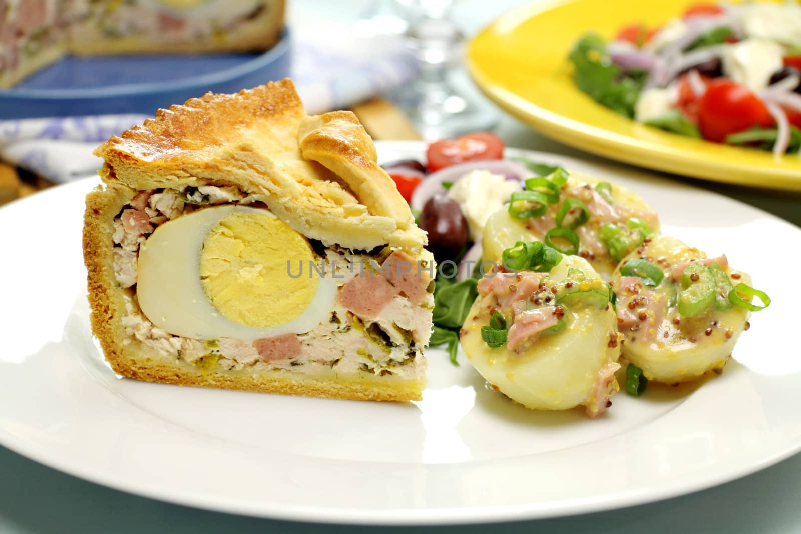 Sliced ham and egg pie with potato salad ready to serve.