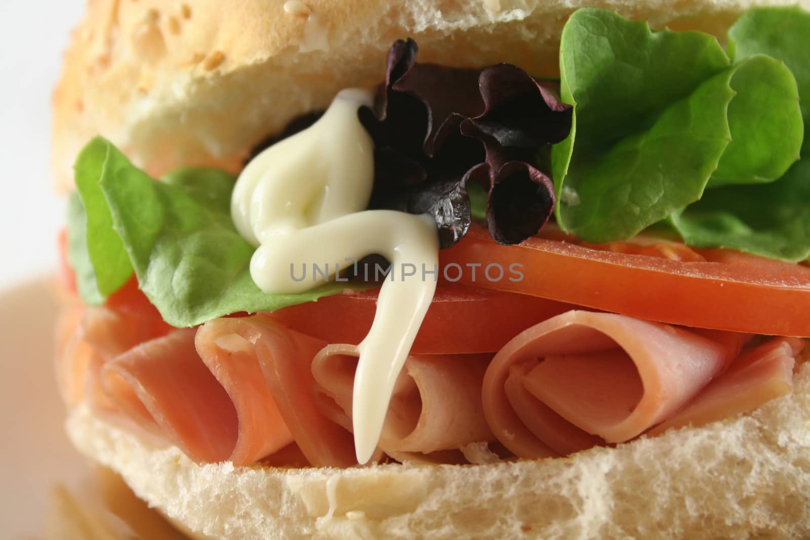 Freshly prepared ham and salad roll with mayo.