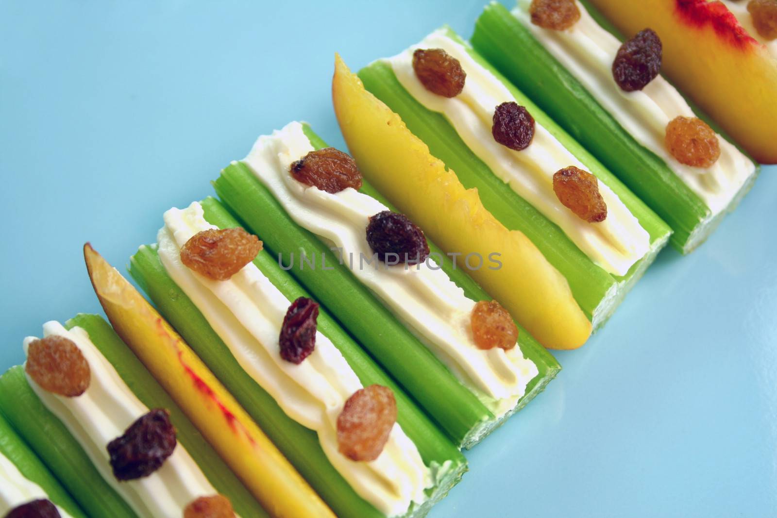 Healthy afternoon snack of celery sticks with cream cheese and sultanas.