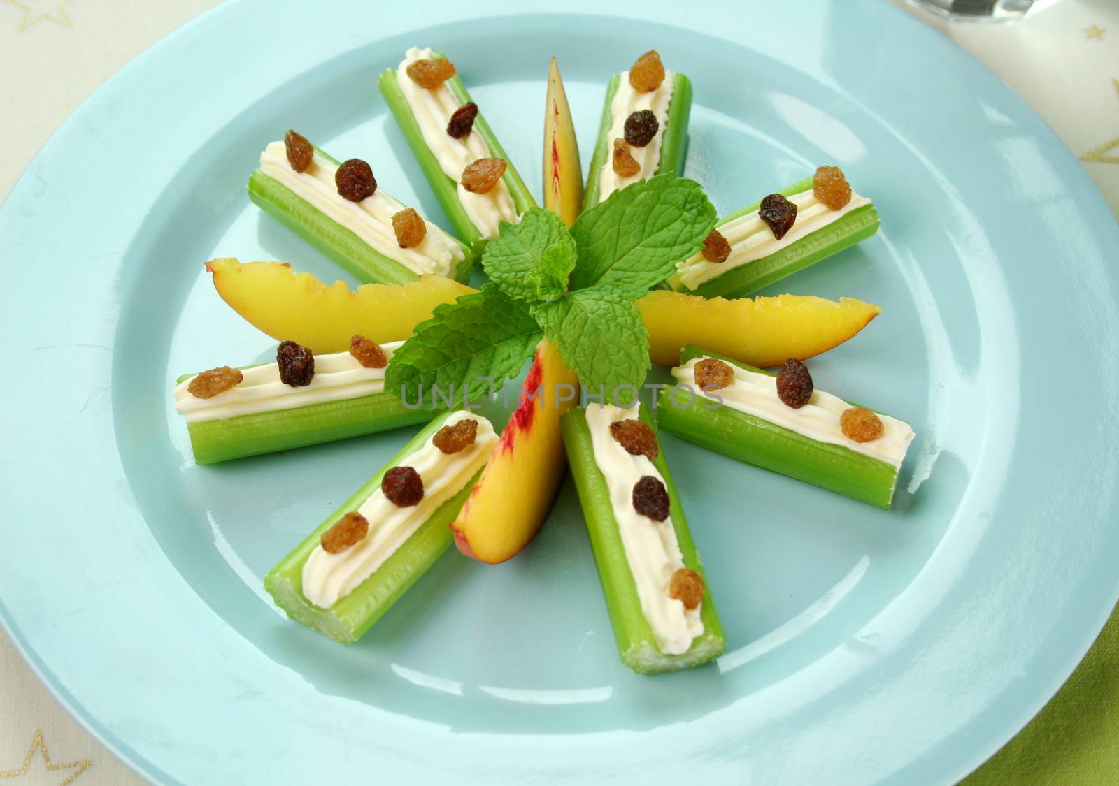 Healthy afternoon snack of celery sticks with cream cheese and sultanas.