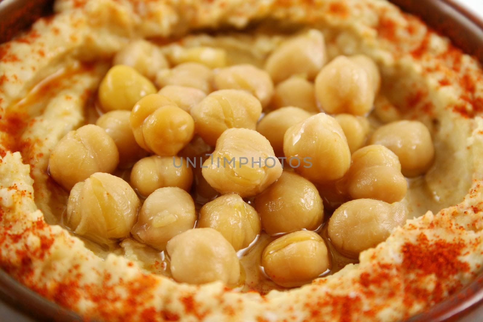 Earthenware bowl with delicious hommus and chickpeas ready for dipping.