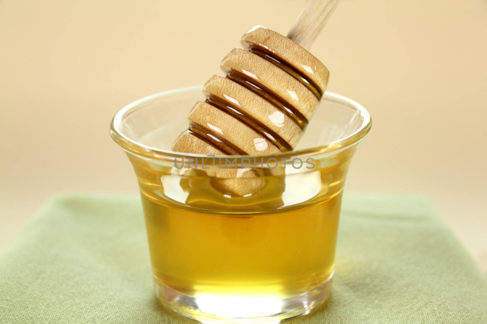 Honey twirler dipped into a glass of honey and about to be lifted.