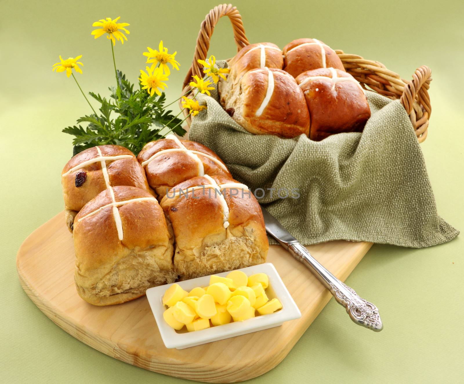 Hot cross buns in a basket and some with butter and daisies.