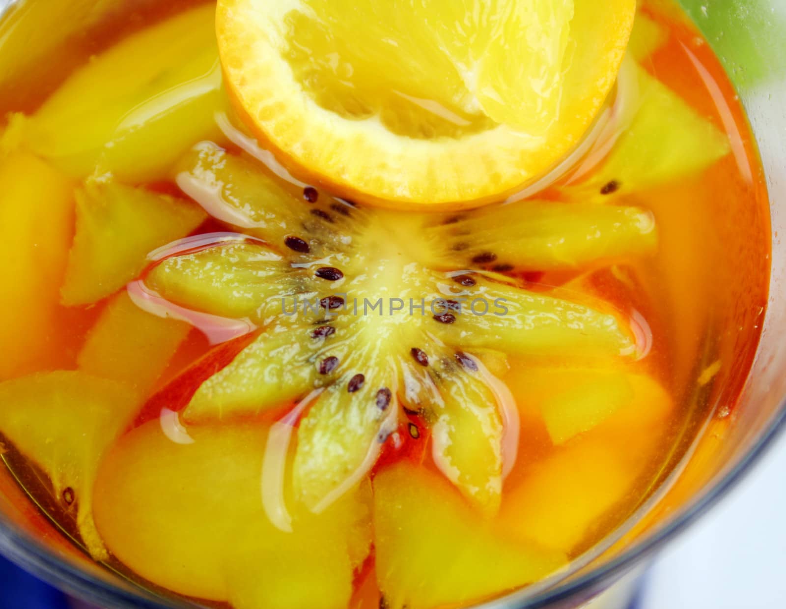 Fresh sliced tropical fruit set in pineapple jelly in a glass.