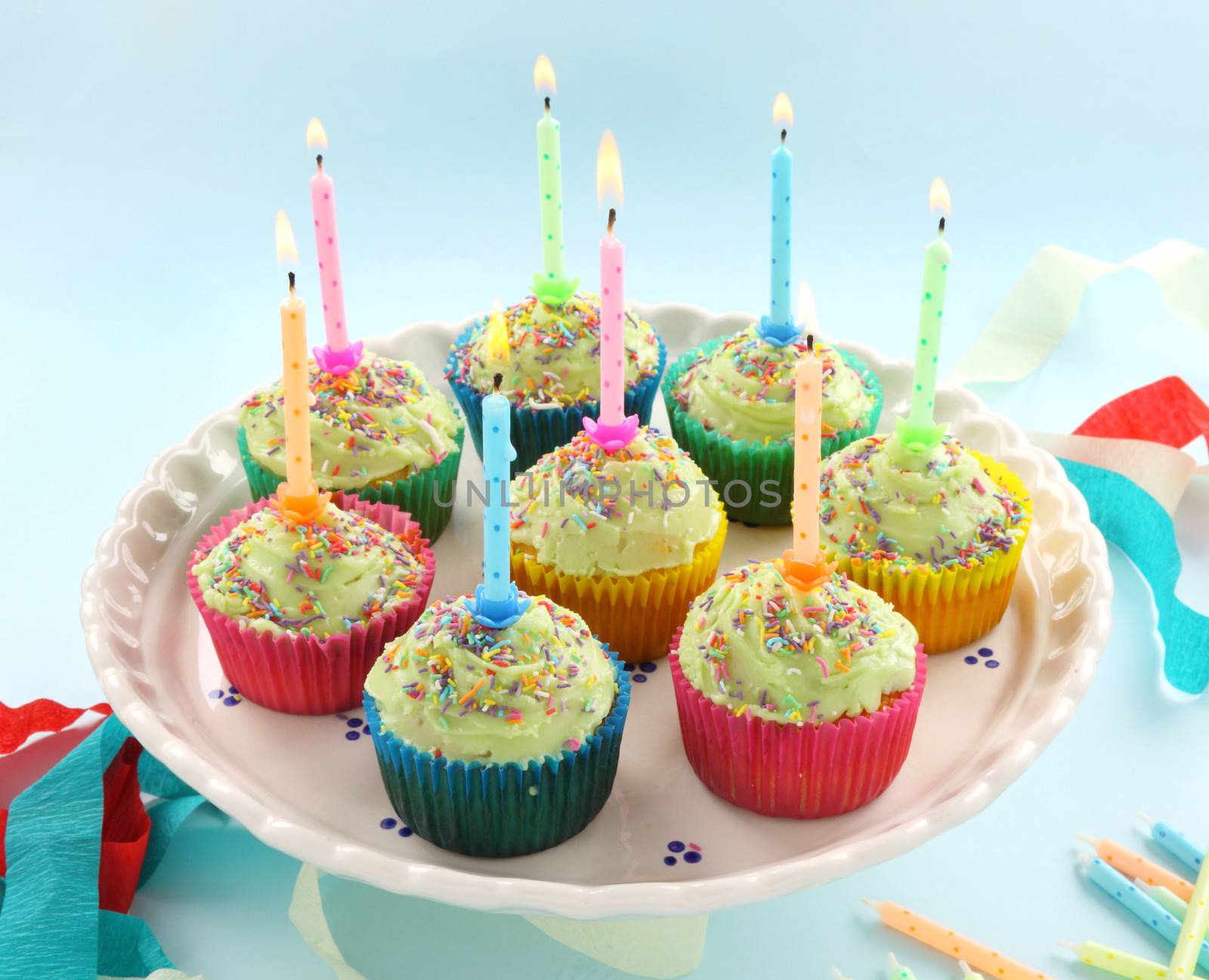 Birthday cup cakes all with their own candles burning.