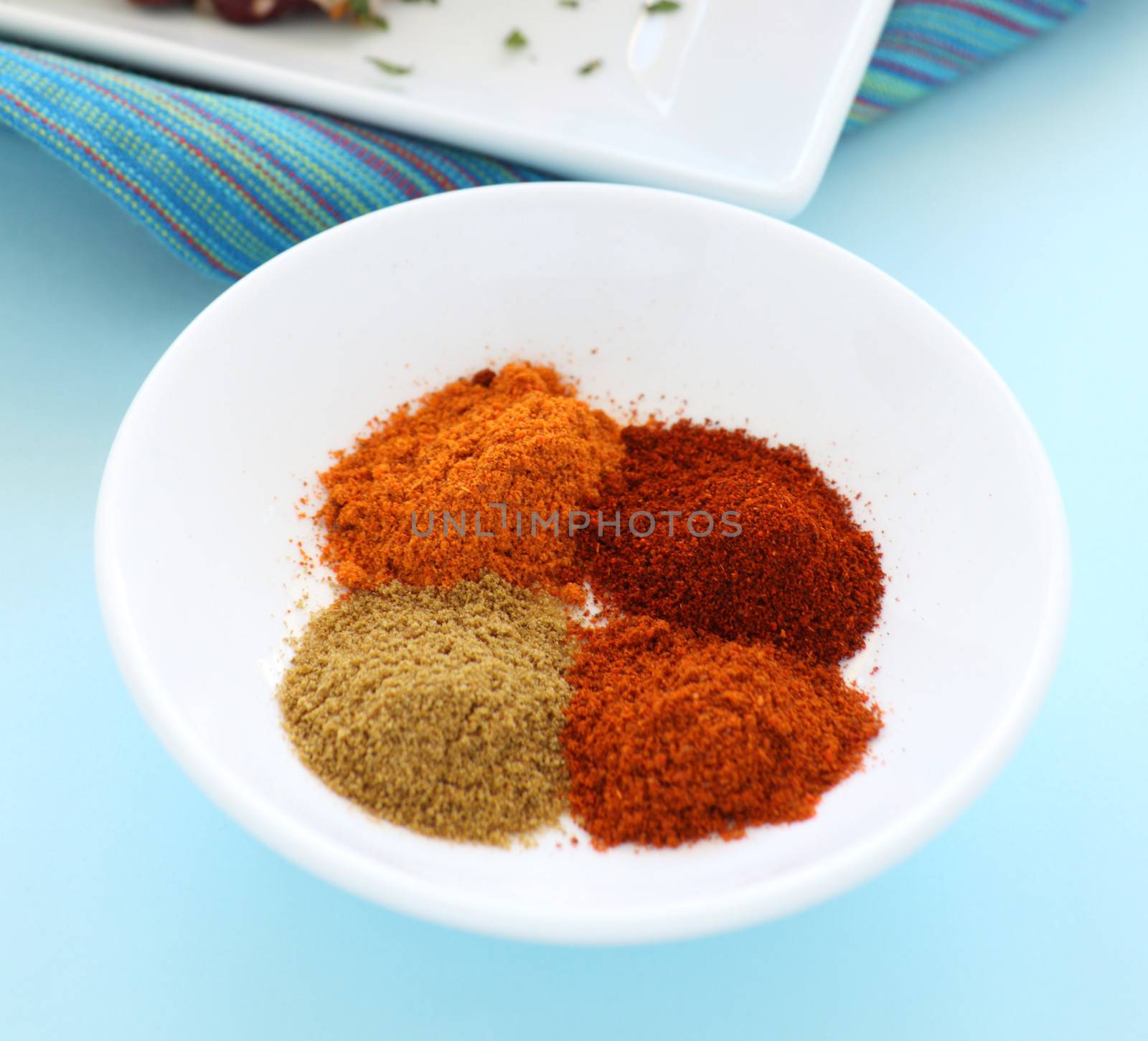 Selection of hot spices including cayene pepper, chilli, cumin and paprika in a bowl.